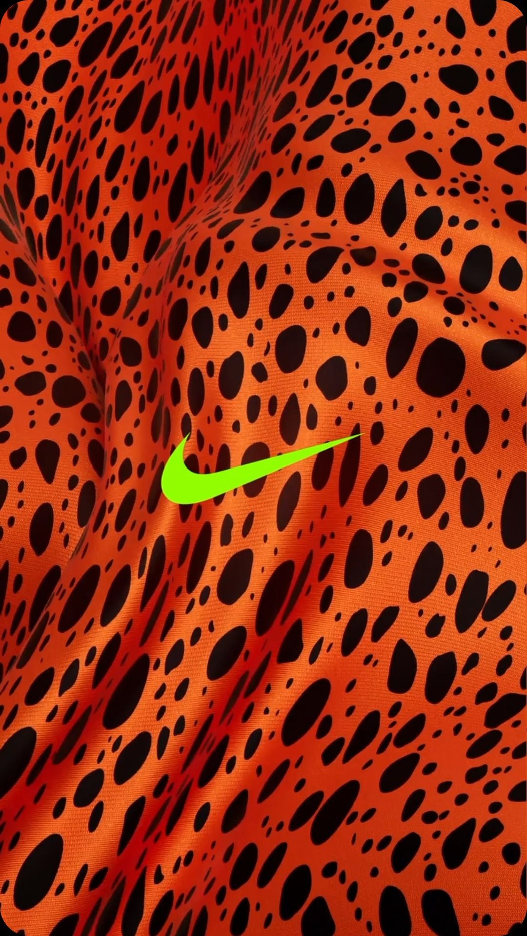 Close-up of orange fabric with black spots and a bright green Nike logo. Abstract shot for fashion or sports brand promotion.