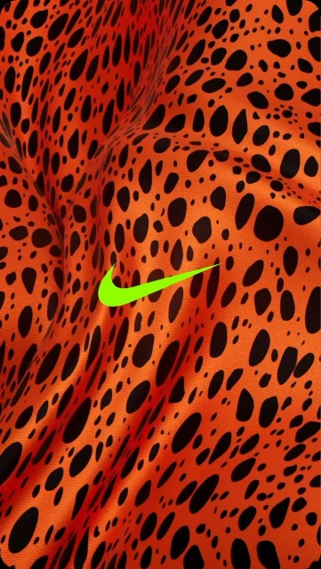 Close-up of orange fabric with black spots and a bright green Nike logo. Abstract shot for fashion or sports brand promotion.
