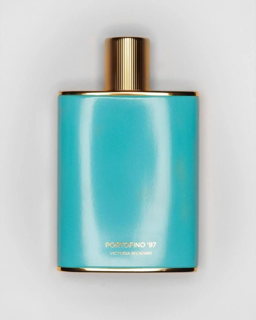 A turquoise perfume bottle with gold accents stands against a white backdrop, featuring the text 'Portofino '97 Victoria Beckham'.
