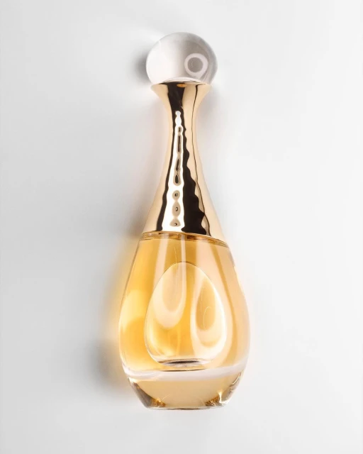 Gold perfume bottle with clear spherical stopper on a white background, product shot for beauty, cosmetics, or fashion marketing.