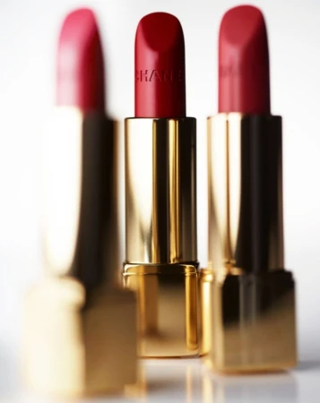 Three red lipsticks with gold tubes are arranged closely together in a beauty or fashion product shot against a white background.