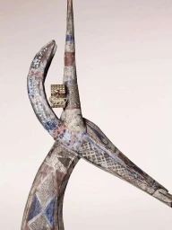 Detailed vertical photograph by Ines Dieleman featuring a gold ring resting on a weathered painted wooden sculpture against a light background.