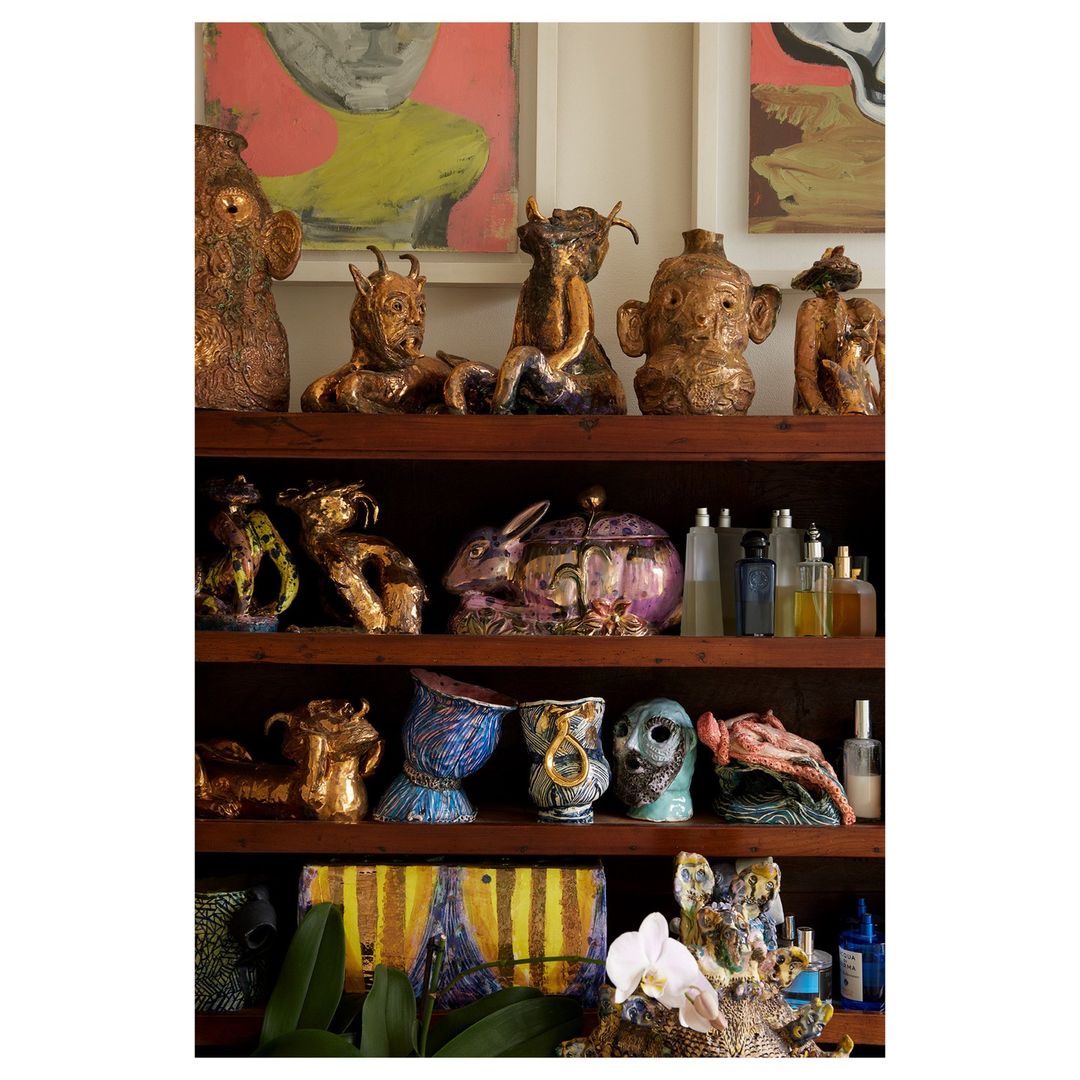Interior shot of shelves displaying an eclectic collection of art pottery, sculptures, and decorative objects, set against wall art.