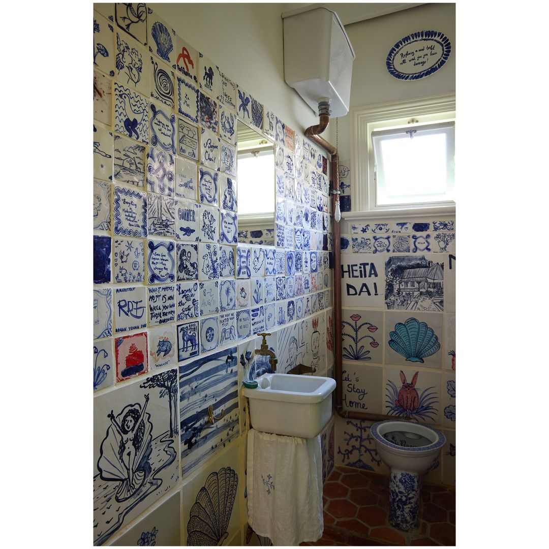 Bathroom interior with custom ceramic tile art covering walls and fixtures, creating a unique and whimsical space with drawings and patterns.