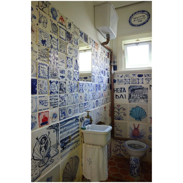 Bathroom interior with custom ceramic tile art covering walls and fixtures, creating a unique and whimsical space with drawings and patterns.