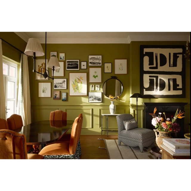 Stylish living space with a dining table set for a meal, elegant chairs, decorative artwork, and a cozy armchair, all illuminated by soft lighting.