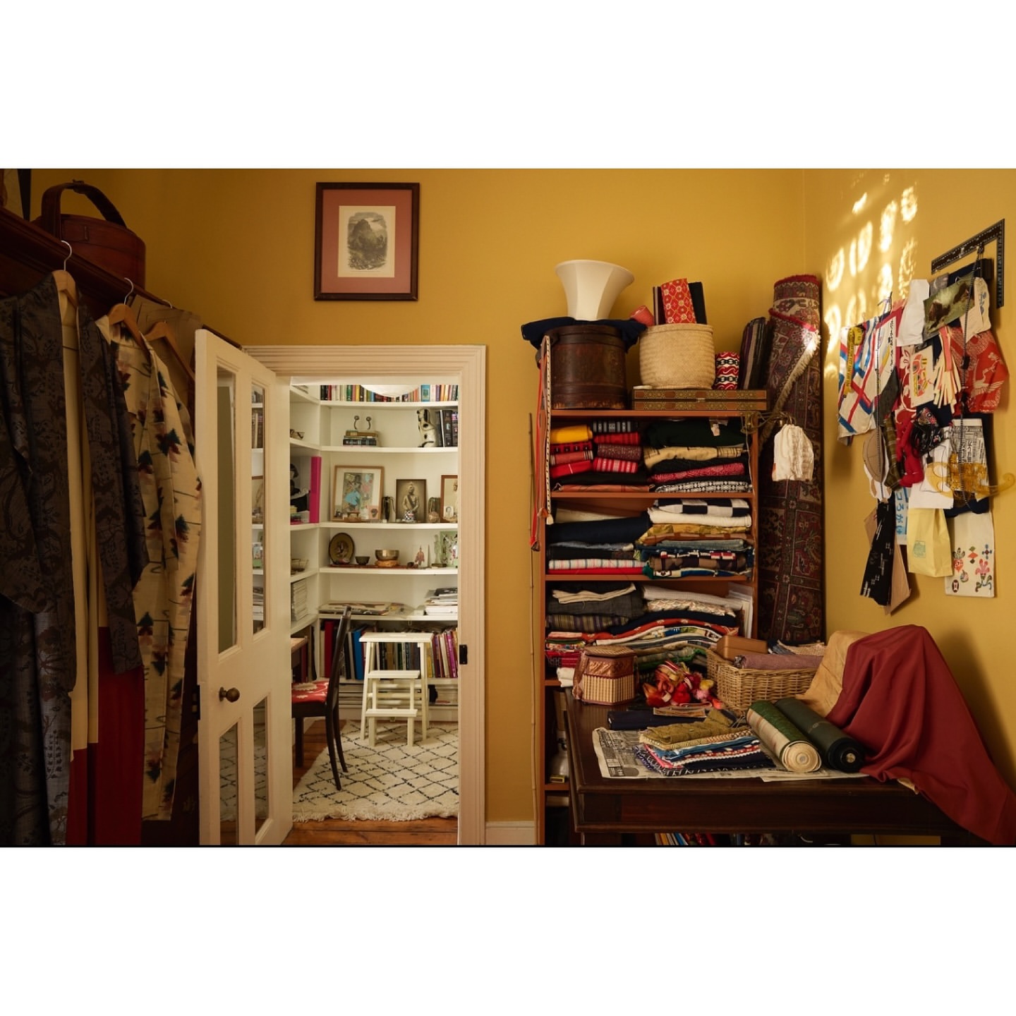 Home interior with wooden shelves filled with folded clothes, decor, and accessories, visible through an open doorway in a cozy space.