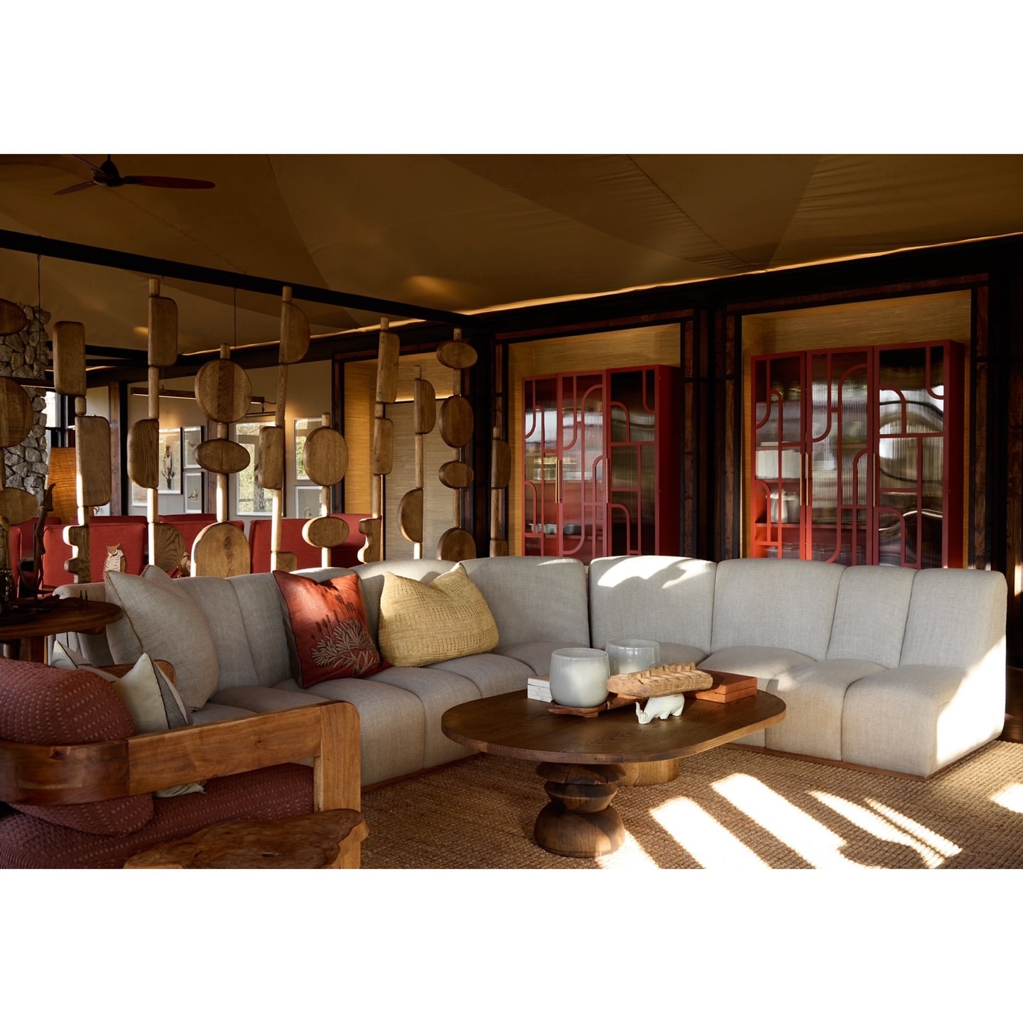 Neutral-toned living room featuring a sectional sofa, wooden coffee table, patterned pillows, textured rug, and architectural woodwork.