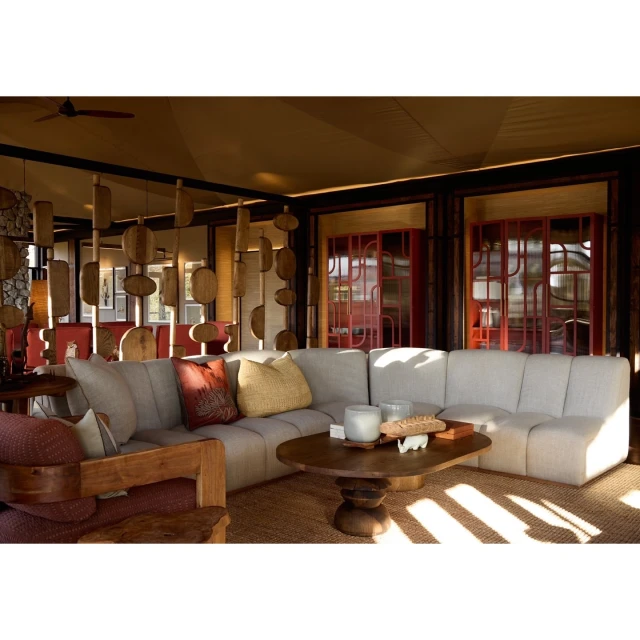 Neutral-toned living room featuring a sectional sofa, wooden coffee table, patterned pillows, textured rug, and architectural woodwork.