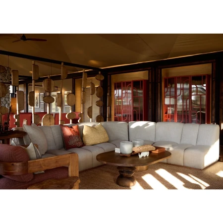 Neutral-toned living room featuring a sectional sofa, wooden coffee table, patterned pillows, textured rug, and architectural woodwork.