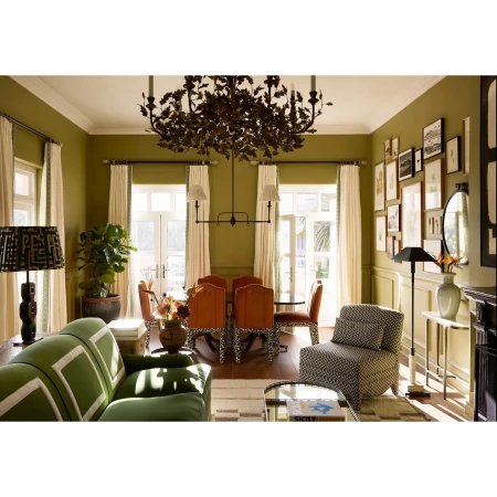 Living room and dining area of an opulent home interior with green walls, stylish furniture, and a modern chandelier centerpiece.