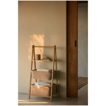 Bathroom interior with wooden shelf ladder featuring storage baskets and towels, set against a cream-colored wall and wooden door frame.