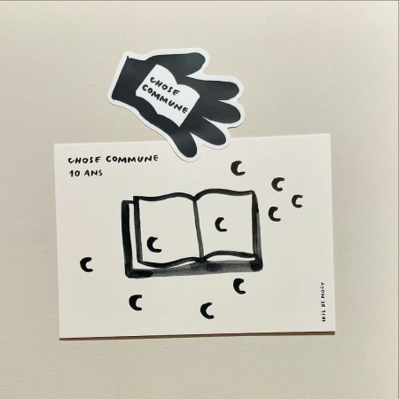 Illustrated book on a white background, accompanied by a hand-shaped black and white sticker holding a miniature book, simple line drawing art.