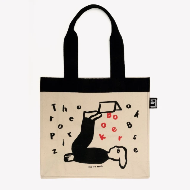 Tote bag featuring a whimsical illustration of a person reading a book upside down, with the text 'The Boxer' in red and black.