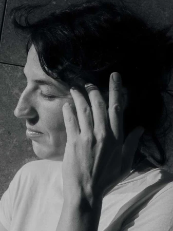 Close-up portrait of a woman with dark hair touching her face, captured in monochrome by photographer Iris Humm.