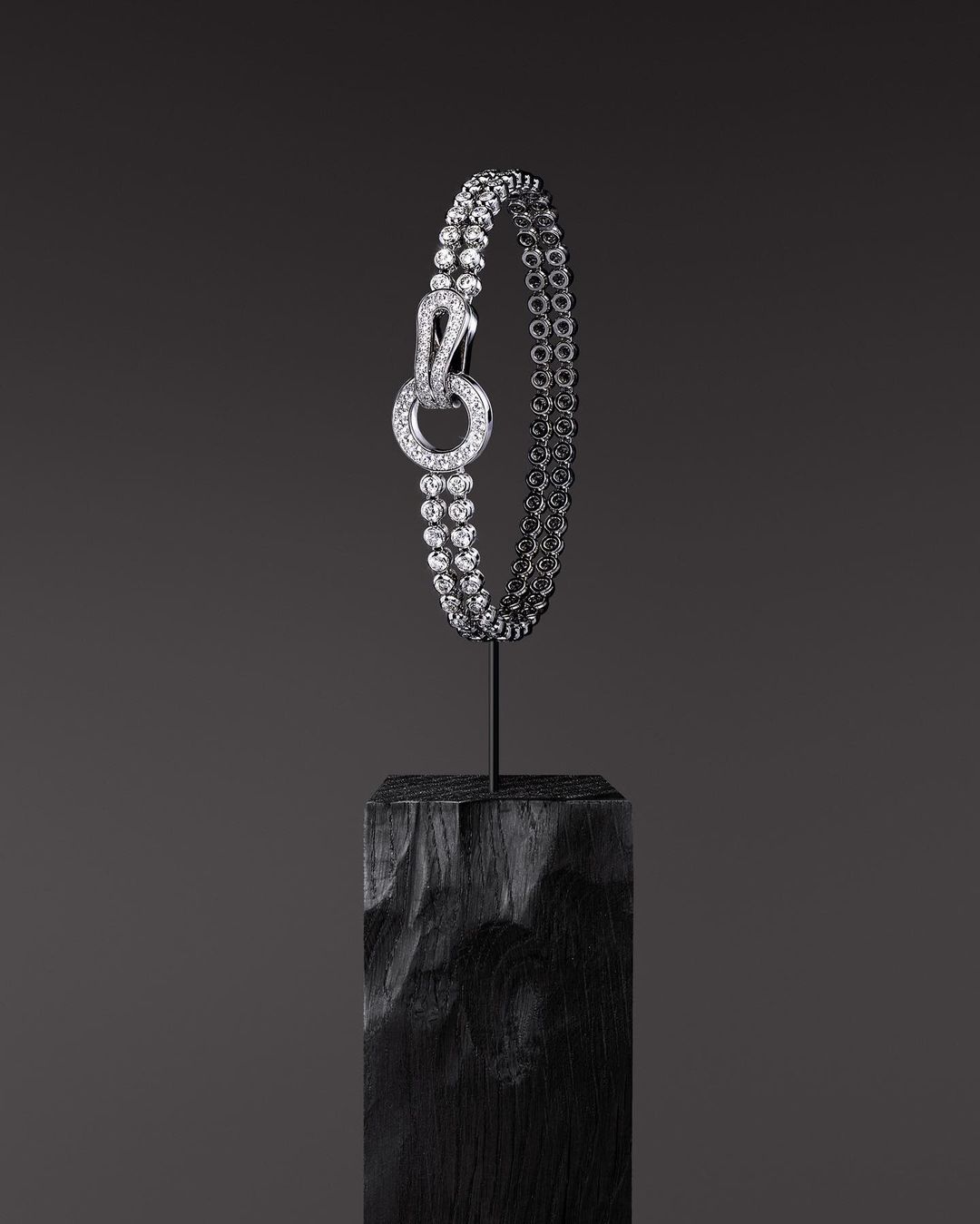 Elegant diamond bracelet displayed on a dark wooden block against a solid dark gray background in a studio setting. Jewelry photography.