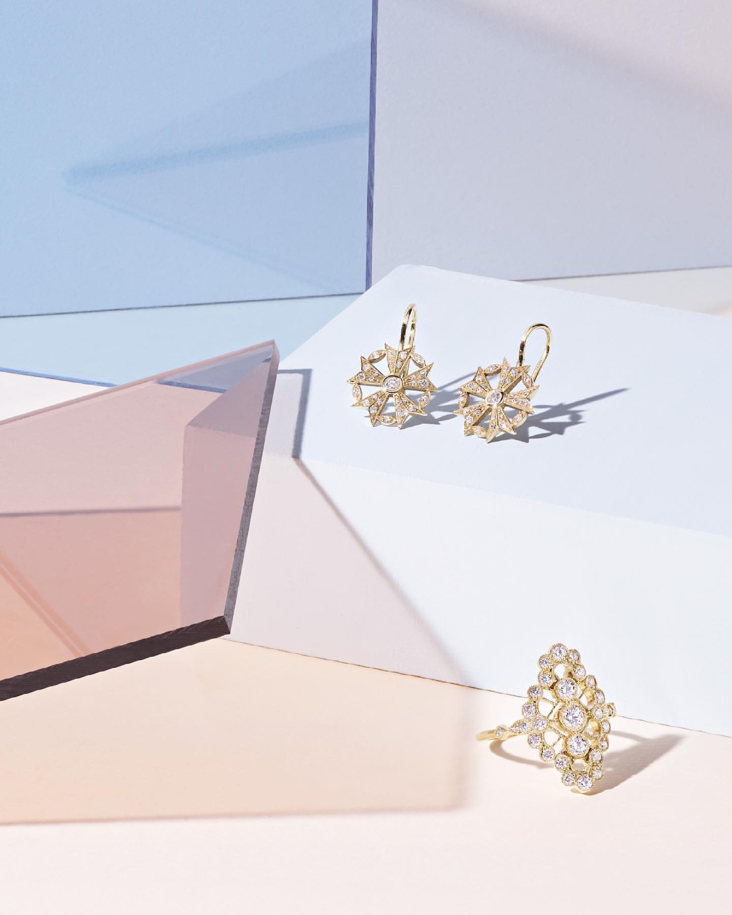 Elegant gold ring and dangling earrings with sparkling gem details, set against a modern pastel backdrop for high-end jewelry promotion.