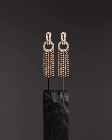 Elegant pair of drop earrings with spherical beads on dark textured stand against a dark grey backdrop, highlighting jewelry craftsmanship.