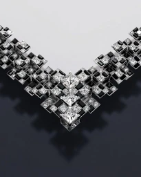 Close-up studio shot of a geometric diamond and black gemstone statement necklace on dark background