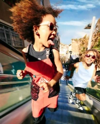 Two children running down an outdoor escalator in London, captured in a candid shot by photographer Isaac Lamb.