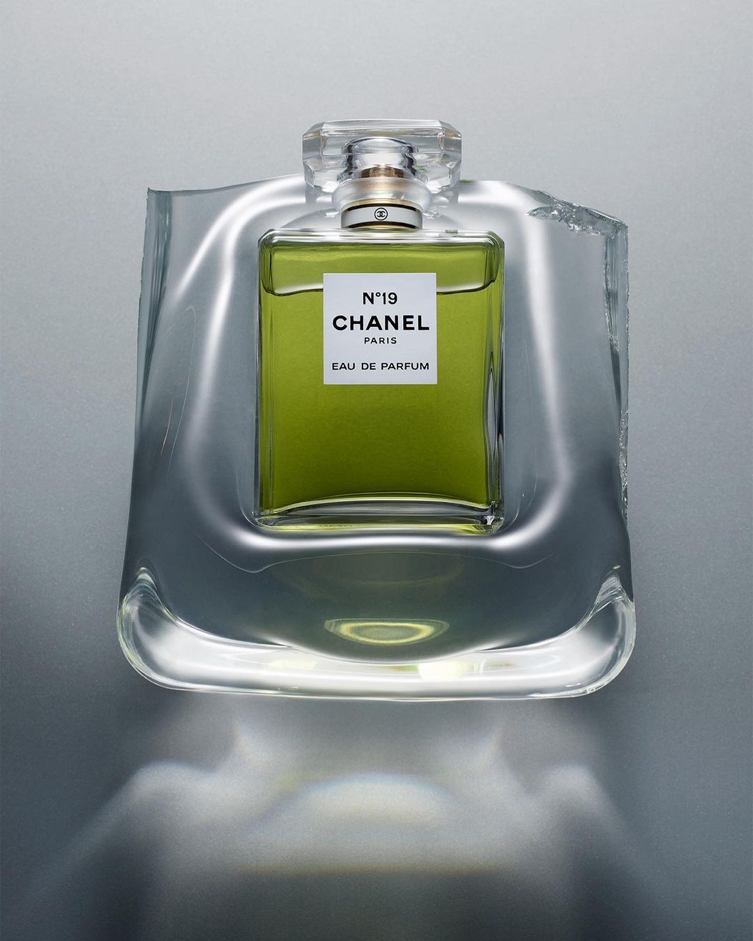 Chanel N°19 Eau de Parfum bottle in a clear sculptural display, showcasing the fragrance's elegant design and vibrant green liquid.