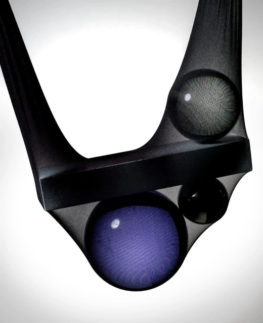 Abstract image with a black bar and three spheres suspended in dark sheer hosiery against a gradient white background.