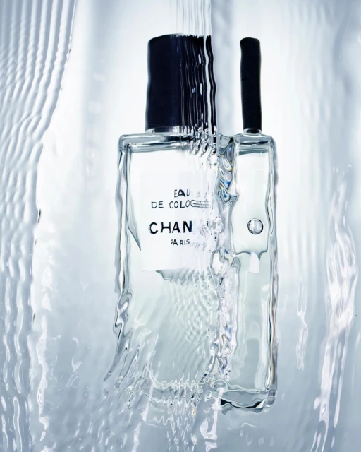 Clear Chanel cologne bottle with water cascading down, showcasing its minimalist design and creating a fresh, clean aesthetic.