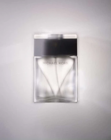Michael Kors perfume bottle on a white surface, showcasing a modern glass design with a black cap and logo for the brand.