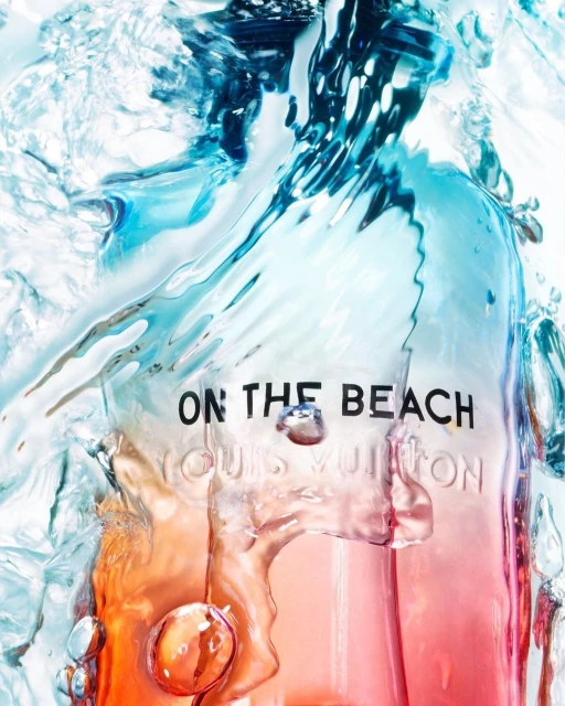 Louis Vuitton 'On the Beach' fragrance bottle under a splash of clear water, featuring an orange to pink color gradient and prominent branding.