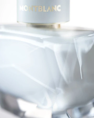 Close-up studio shot of a Montblanc fragrance bottle with a smooth, light-blue surface and gold lettering on a white background.