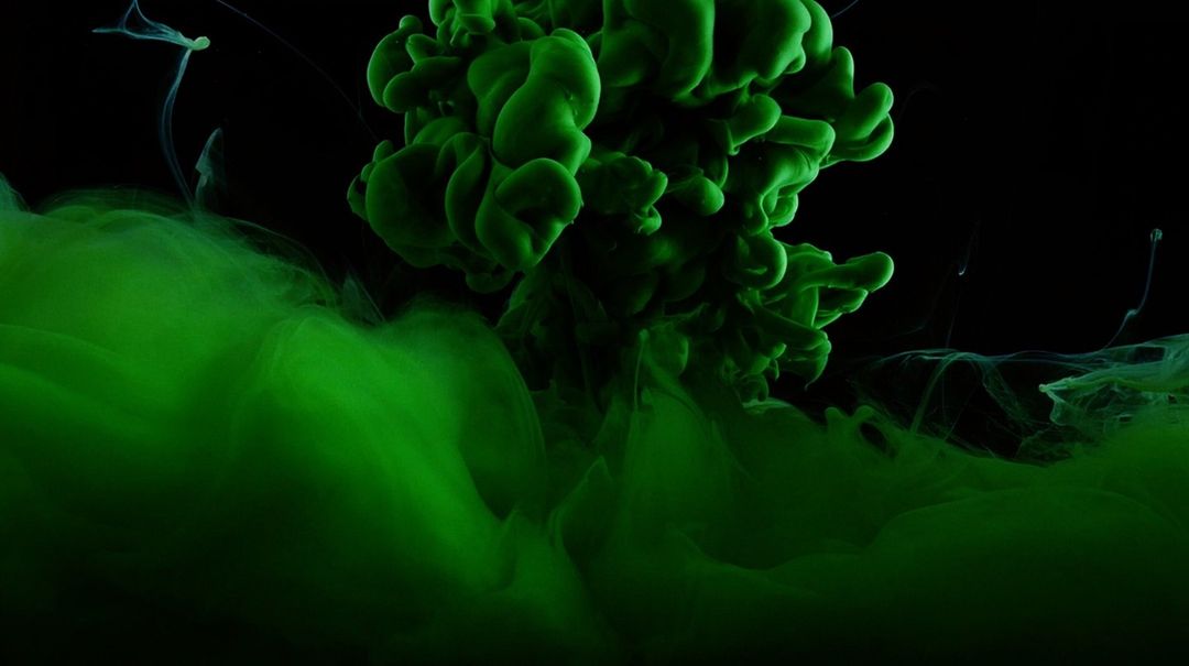 A vibrant green liquid explosion against a stark black background creates a visually striking abstract image.
