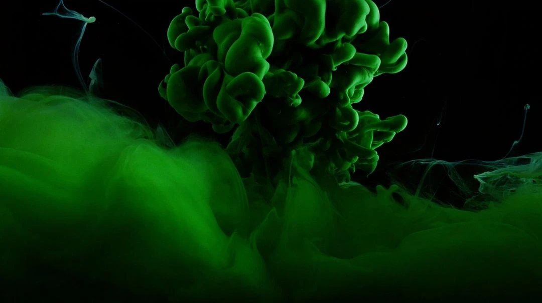 A vibrant green liquid explosion against a stark black background creates a visually striking abstract image.