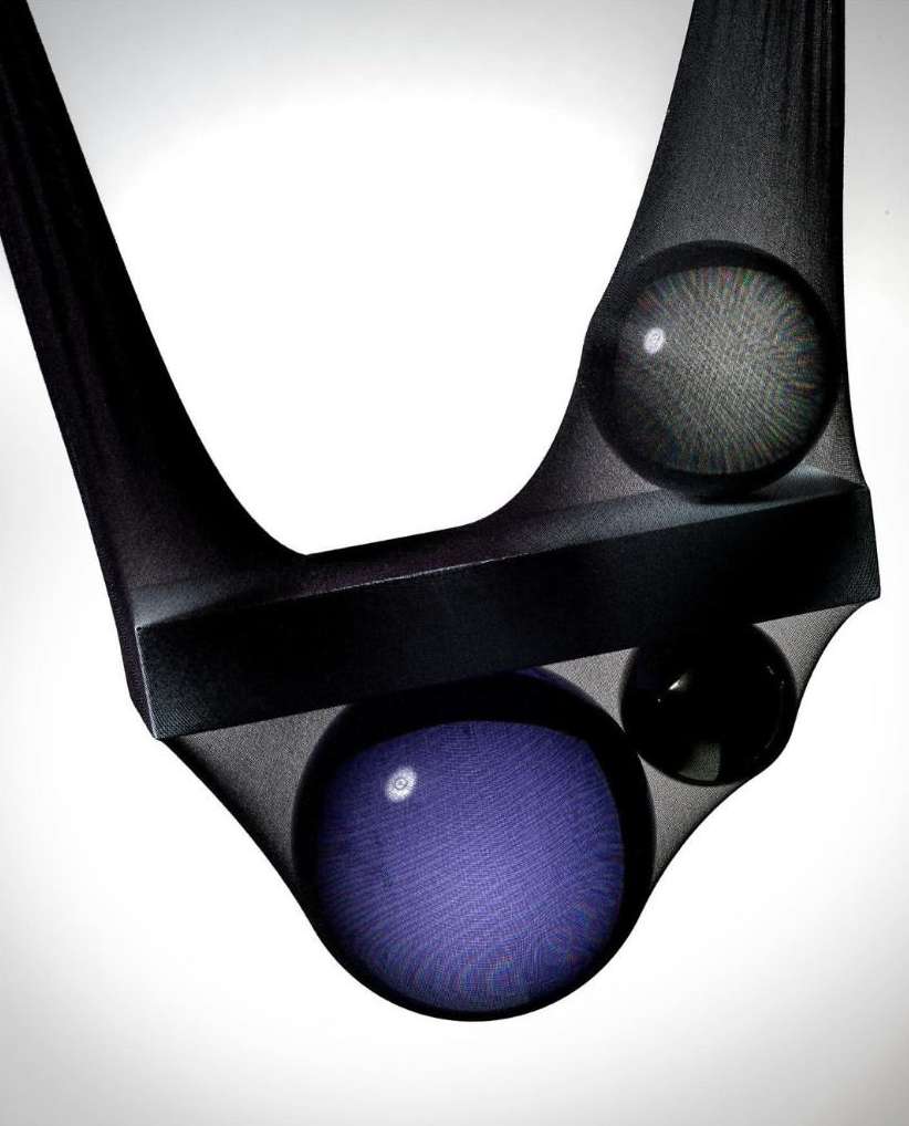 Abstract studio image of geometric shapes including a rectangle and spheres, held in place with sheer black fabric against a white background.