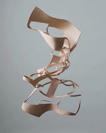 Abstract art sculpture made from layered tan leather strips suspended against a gray background, creating a surreal, textured form.
