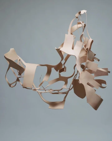 Abstract design featuring irregularly cut strips of pale beige leather suspended against a light grey background, creating a dynamic form.