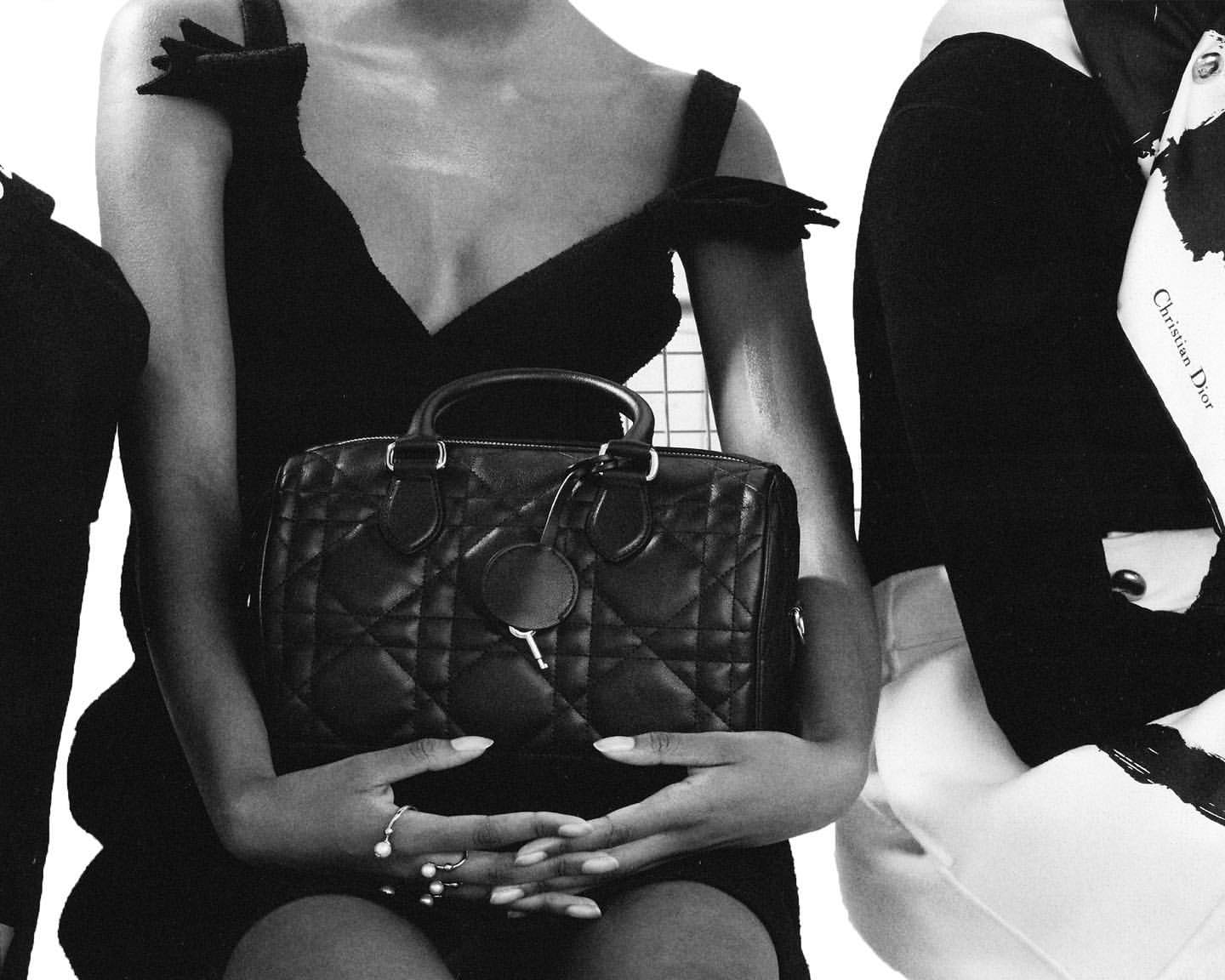 Monochromatic fashion shot of a woman holding a dark quilted handbag, showcasing a stylish and elegant look with jewelry accents.