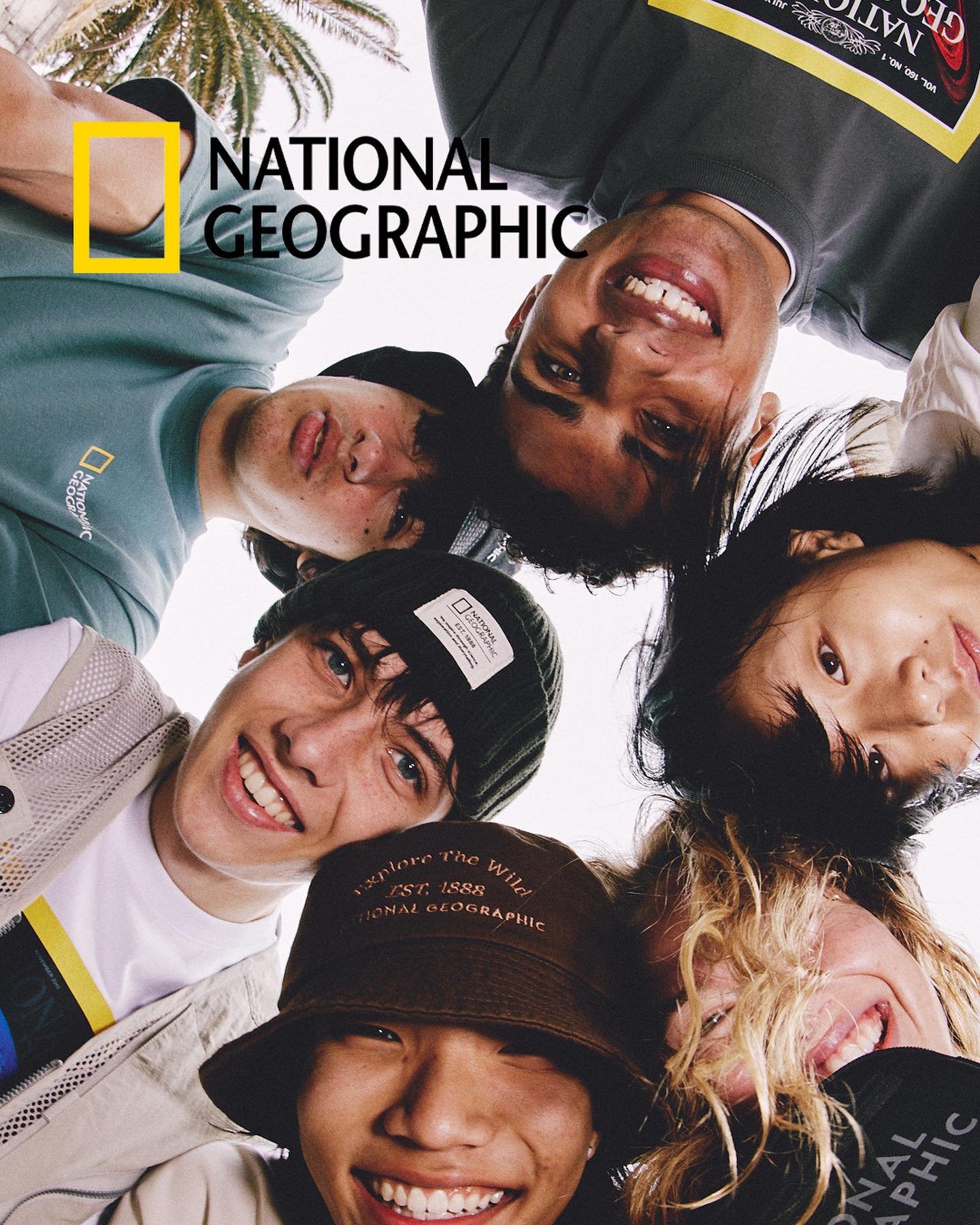 Group of smiling young adults in an eye-level shot, wearing casual clothing, posing in an indoor setting, and exhibiting a joyful mood.