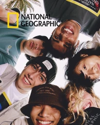 Low angle view of a diverse group of young adults smiling in a tight huddle against an outdoor sky background