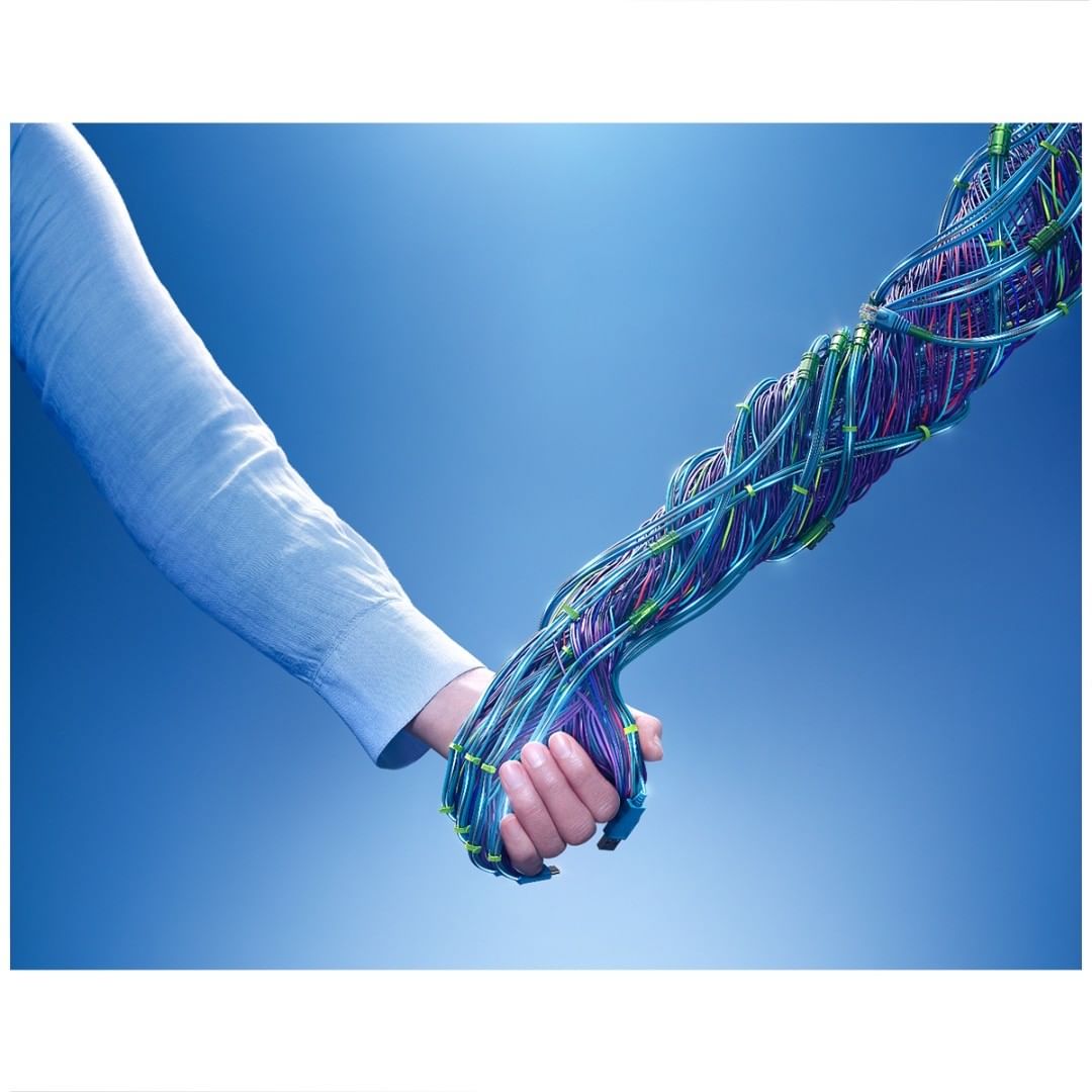 Digital composite of human and robotic hand handshake on graduated blue background representing future technology and artificial intelligence.