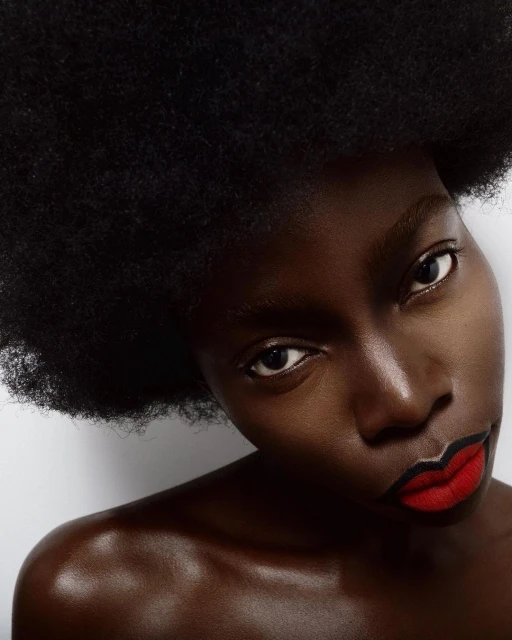 Close-up portrait of a Black woman with red lipstick against a white background showcasing beauty, makeup, and facial features.