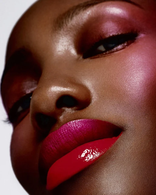 Close-up studio shot of a Black woman with pink eyeshadow and vibrant red lipstick, showcasing beauty and cosmetics, portrait orientation.