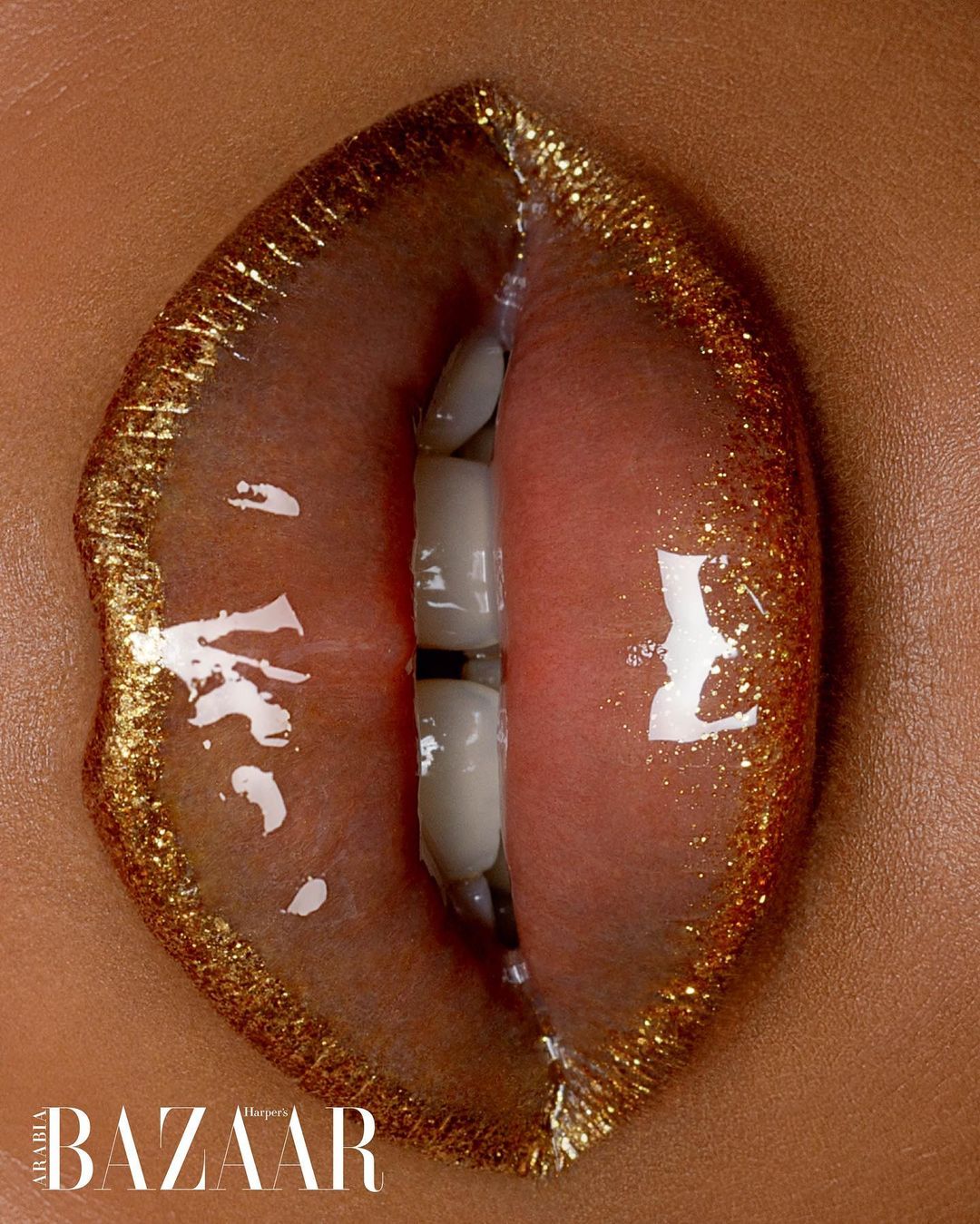 Extreme close-up of a woman's lips with gold glitter lipstick and visible teeth for a beauty and fashion editorial, high-fashion photography.