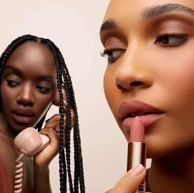 Two women of color showcase matte lipstick with a retro telephone; beauty and fashion-forward cosmetic marketing concept.