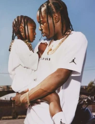 Black man holding a child in a white t shirt against an outdoor sky background