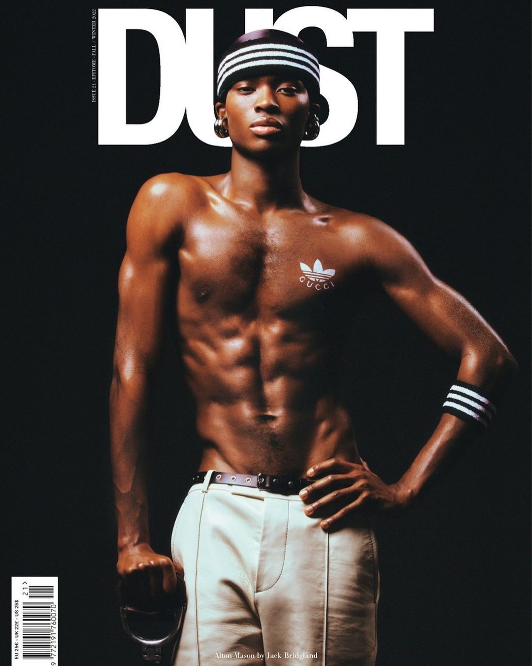 Magazine cover featuring a muscular Black male model with a shaved head, wearing white athletic pants and a headband, posing against a dark background.