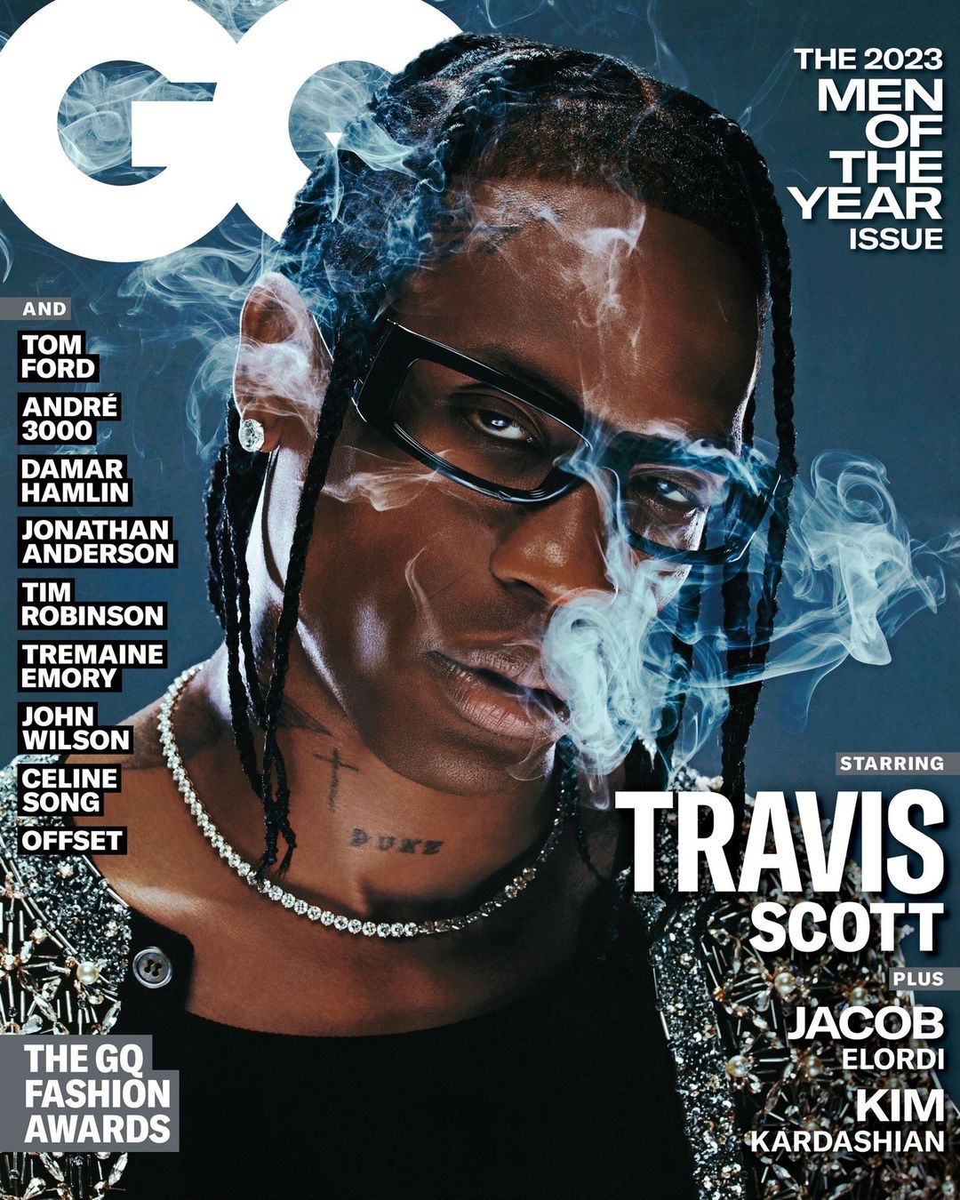 GQ magazine cover featuring Travis Scott in glasses with smoke, wearing a diamond necklace and patterned jacket, on a blue background.