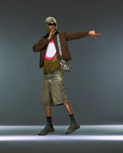 A person in a light green balaclava, brown jacket, graphic tee, and shorts poses in a studio with a cross body bag and athletic shoes.