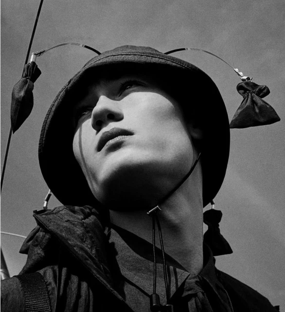 Close-up shot of an adult with fair skin wearing a dark bucket hat and dark clothing, captured with an upward angle against a bright sky.