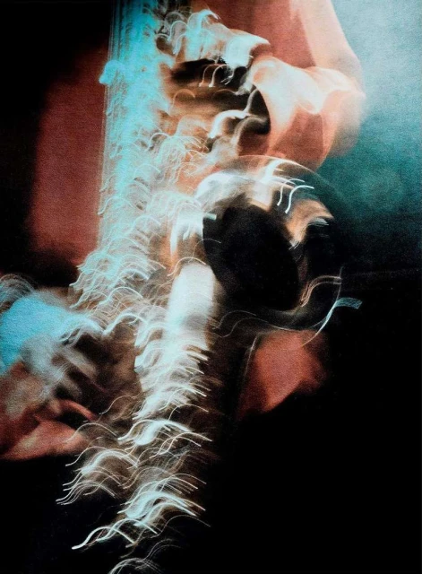 Abstract image featuring a musician with a trumpet, captured with motion blur and long exposure techniques in a dark environment.