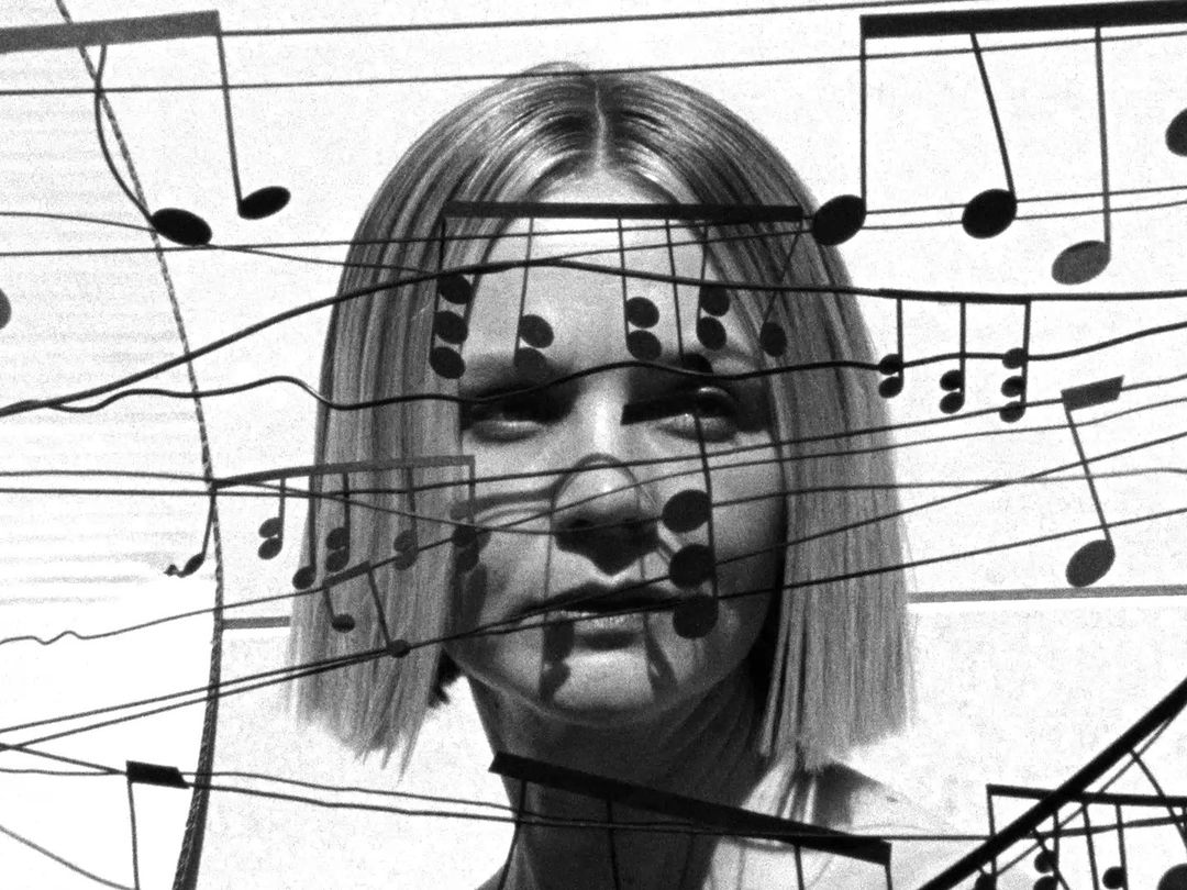 Monochrome portrait of a woman with short blonde hair, overlaid with musical notes and staff lines, creating a blended visual effect.